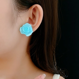 Gros plan d'une boucle d'oreille rose en résine bleu clair portée par un mannequin