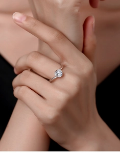 Detailed close-up of a round cut moissanite diamond ring set in silver on a hand