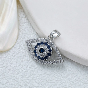 Silver evil eye pendant with blue and white zircons on a white textured background