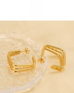 Macro shot of triple-layered titanium steel earrings with a twisted texture and gold finish