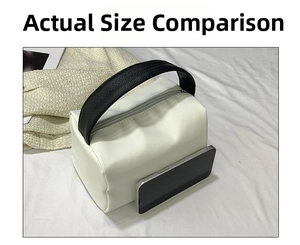 Size comparison of white matte leather handbag next to a smartphone on white fabric