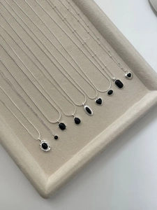 Detailed arrangement of S925 silver necklaces with black agate pendants on a grey tray