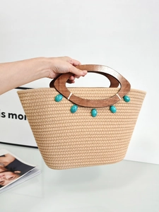 Woven tote bag with wooden handles and turquoise beads in a minimalist setting