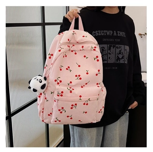 Pink corduroy backpack with cherry pattern and panda plush pendant shown by model