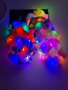 Detailed close-up of colorful glowing LED satin scrunchies in dark background