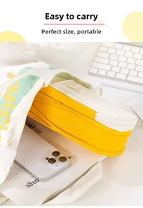 Detail view of a yellow and white canvas stationery bag with wide-opening metal zipper