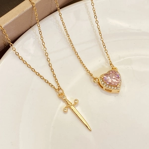 Detail of gold titanium necklaces with a pink heart zircon and a sword-shaped pendant
