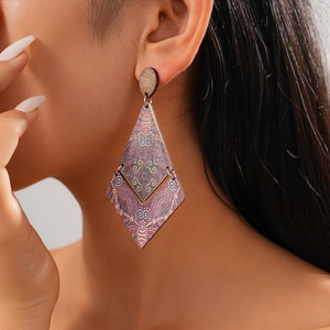 Close-up of a model wearing large geometric rhombus wood earrings with paisley print