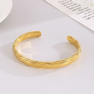 Macro view of French vintage gold twisted rope texture on a C-shaped steel cuff bracelet