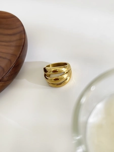 Dettaglio dell'anello multistrato placcato oro su vassoio di legno con luce soffusa