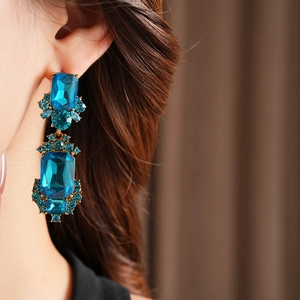 Close-up of vintage geometric blue crystal earrings on model with bronze finish