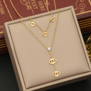 Close-up of double-layered gold necklace with evil eye charms and heart zircon pendant