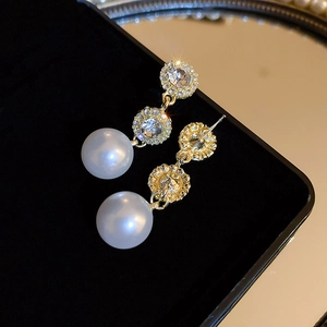 Close-up of luxury pearl earrings with sparkling rhinestones in a black velvet jewelry box