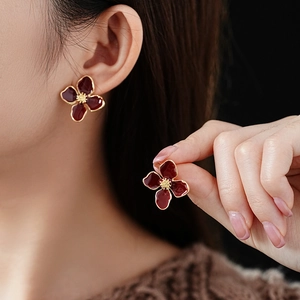 Detail of vintage flower earrings with dark red enamel petals and gold plating