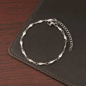 Silver chain bracelet with droplet pendants and lobster clasp on leather and wood