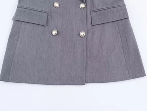 Détail du blazer gris croisé avec boutons argentés et poches à rabat