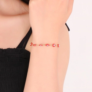 Detail eines roten Evil Eye Armbands mit 18K Vergoldung am Handgelenk eines Models