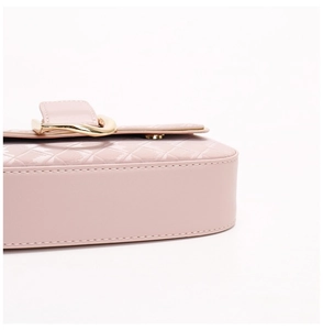 Détail de sac à bandoulière matelassé rose élégant avec boucle en métal doré et belles coutures.
