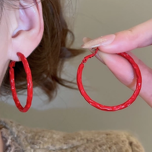 Close-up of red enamel hoop earrings with a unique hammered metal texture and glossy finish