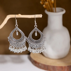 Detailed view of vintage silver hollow tassel earrings hanging on a decorative branch