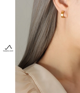 Close-up of a minimalist 18k gold plated stainless steel hoop earring worn by a model