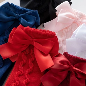 Detailed view of knitted toddler socks with large satin bows in multiple colors