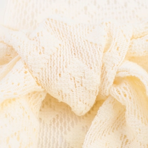 Gros plan sur la maille dentelle crème d'une robe longue élégante à taille nouée