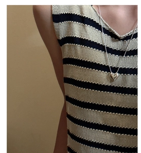 Detailed view of an S925 silver heart necklace over a black and white striped knit vest