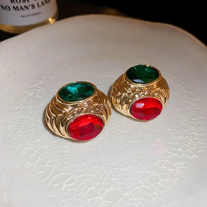 Close-up of vintage heart earrings with red and green gems on a ceramic plate