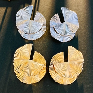 Macro detail of irregular textured fan-shaped earrings in polished gold and silver metal