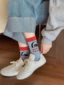 Detail of grey-blue cotton socks with red trim and cat embroidery on a wooden floor