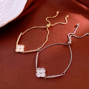 Adjustable gold and silver clover bracelets with cubic zirconia on red silk background