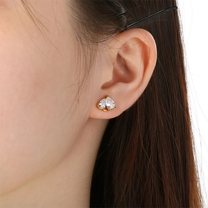 Detail of elegant gold stud earring with pear-cut zircon stones on a model's earlobe