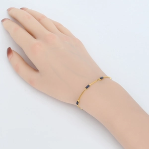 Detail of a minimalist gold bracelet featuring four rectangular deep blue gemstones