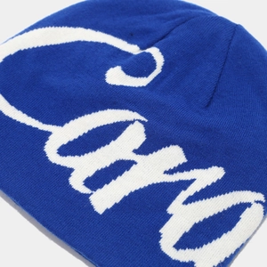 Detail of royal blue knitted beanie showing high-quality white jacquard lettering texture
