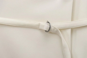 Detailed close-up of cream wrap blazer waist belt with silver metal D-ring buckle
