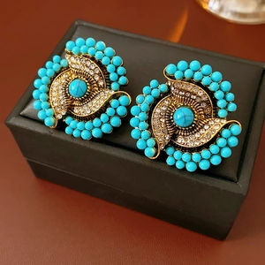 Close-up of vintage flower earrings with turquoise and rhinestones on a black box