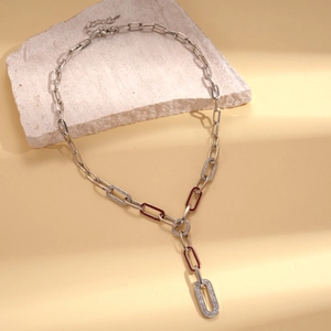 Close-up of silver chain necklace with red enamel and pavé rhinestones on beige stone