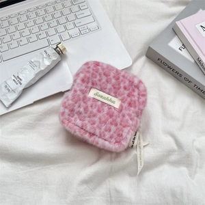 Detail of pink leopard plush pouch featuring a logo label and a decorative ribbon strap