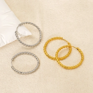 Minimalist twisted rope hoop earrings in gold and silver finish on textured background