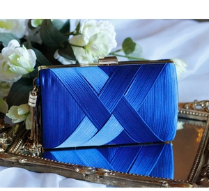 Detail of blue satin pleated clutch bag with gold metal frame and silk fringe charm