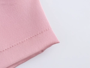 Détail de la texture du tissu rose montrant les coutures et la finition plissée du vêtement