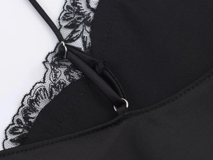 Detailed macro view of black lace trim and adjustable shoulder straps with metal buckles