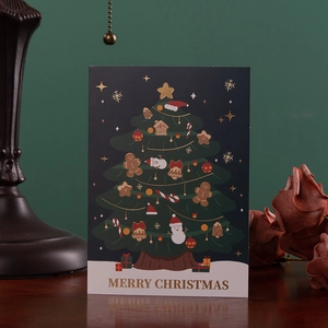 Deep green Christmas card featuring a gold foil tree design on a rustic wooden table