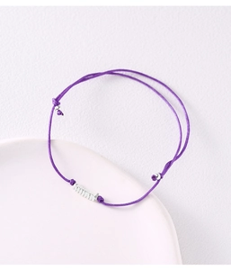 Detailed shot of purple braided rope bracelet with silver bead charms on a tray