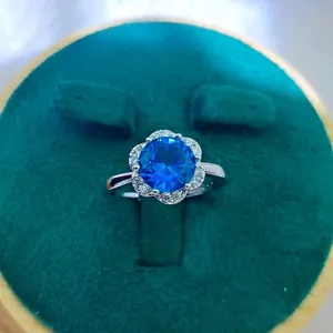 Detail view of flower-shaped ring with blue center stone in green velvet jewelry box