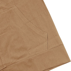 Detailed close-up of brown linen fabric texture and double-stitch sewing on the pocket