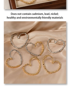 Macro shot of liquid metal heart earrings in gold and silver on champagne silk fabric