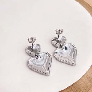 Detail view of silver heart drop earrings featuring double layered mirror polished finish