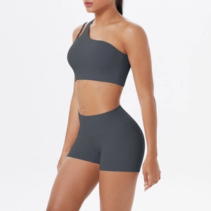 Detail of dark grey one-shoulder sports bra and high-waisted shorts set on a model